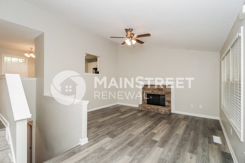 a living room with a fireplace and a ceiling fan