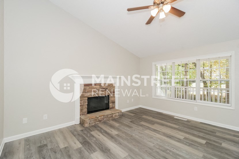 a living room with a fireplace and a ceiling fan
