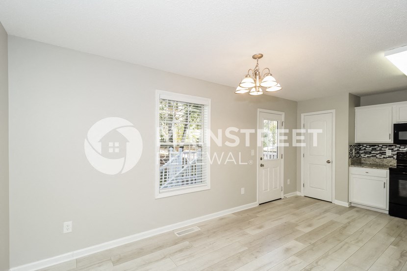 a kitchen and living room with a white door and a window