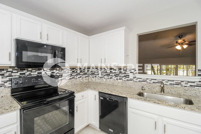a kitchen with white cabinets and black appliances and a sink