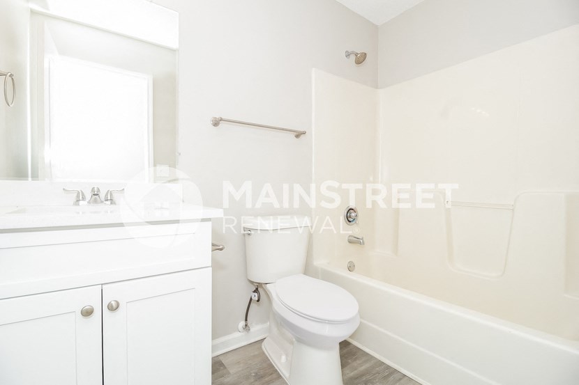 a white bathroom with a toilet and a tub