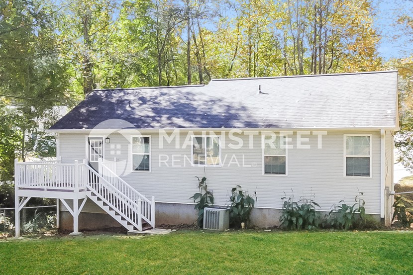 a small white house with a white deck and a porch