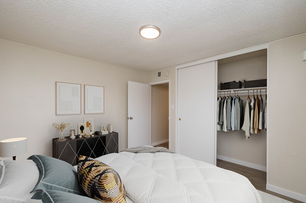 A bedroom with a bed, a wardrobe, and a nightstand with a lamp.