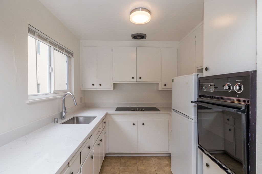 a kitchen with white cabinets and black appliances and a sink