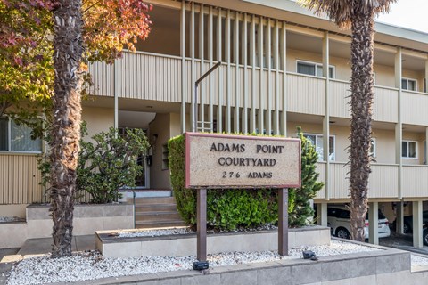 A sign that says Adams Point Courtyard stands in front of a building.