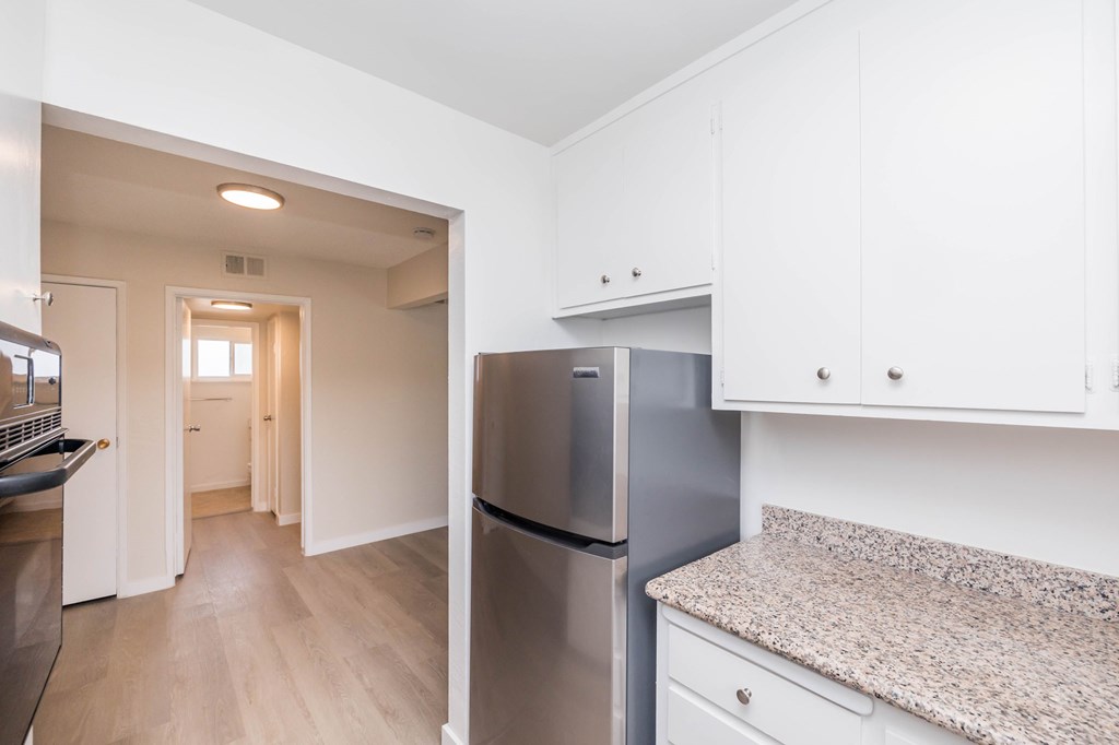 A kitchen with a granite counter top and a refrigerator.