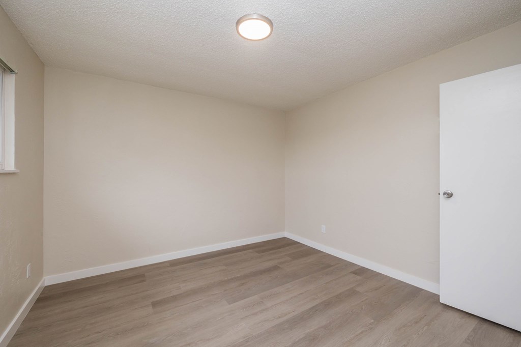 A room with a white door and a window on the left side.