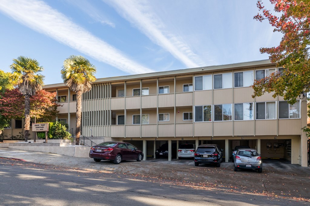 A parking lot with cars and a building with palm trees in front.
