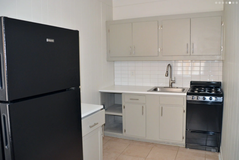 a kitchen with white cabinets and a black refrigerator