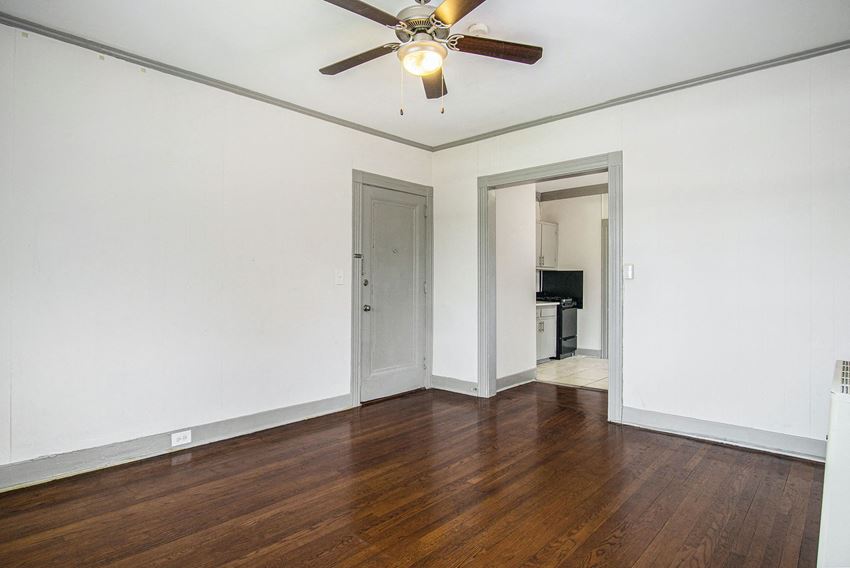 an empty living room with wood floors and a ceiling fan