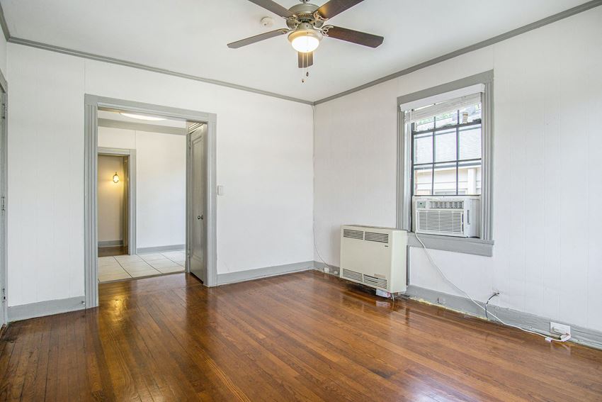 an empty living room with wood floors and a ceiling fan