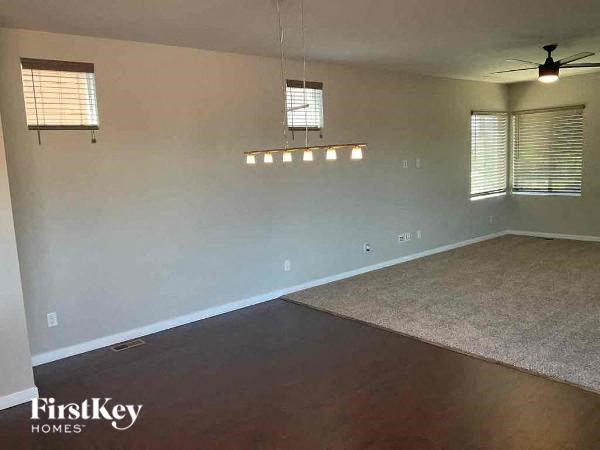 an empty living room with a rug and a ceiling fan