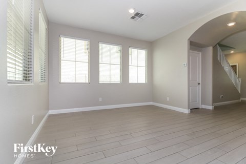 A spacious room with wooden flooring and a staircase on the right.
