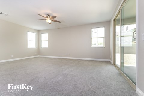 A spacious room with a ceiling fan and two windows.