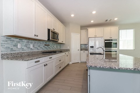 A kitchen with white cabinets and a granite countertop.