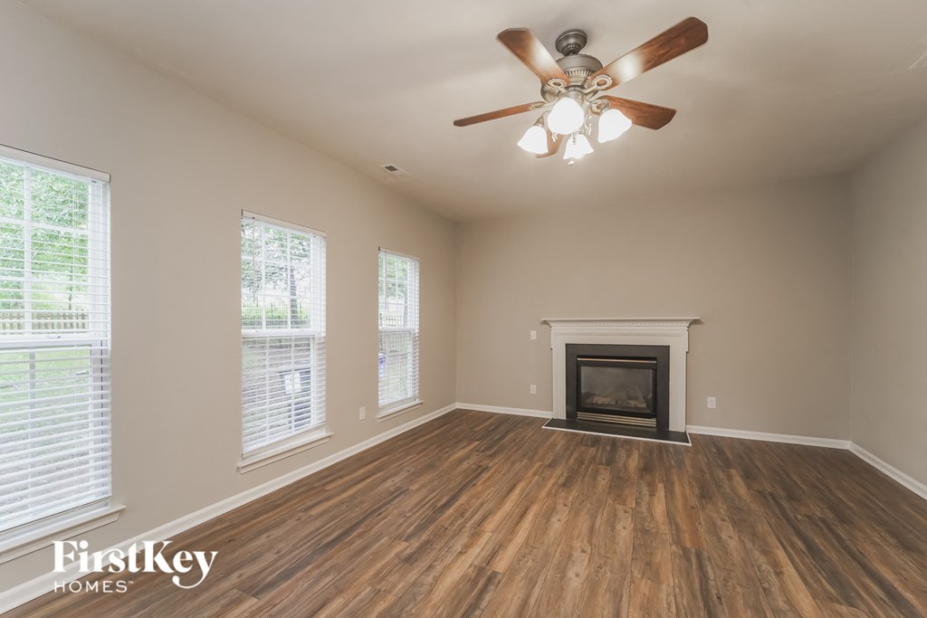 an empty living room with a fireplace and a ceiling fan