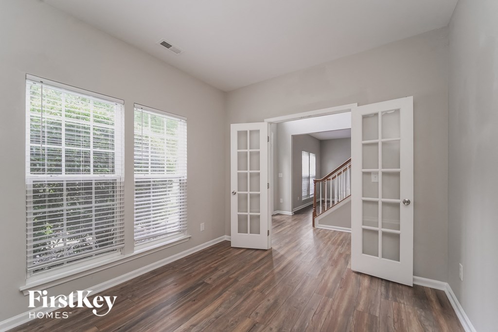 an empty living room with large windows and a staircase