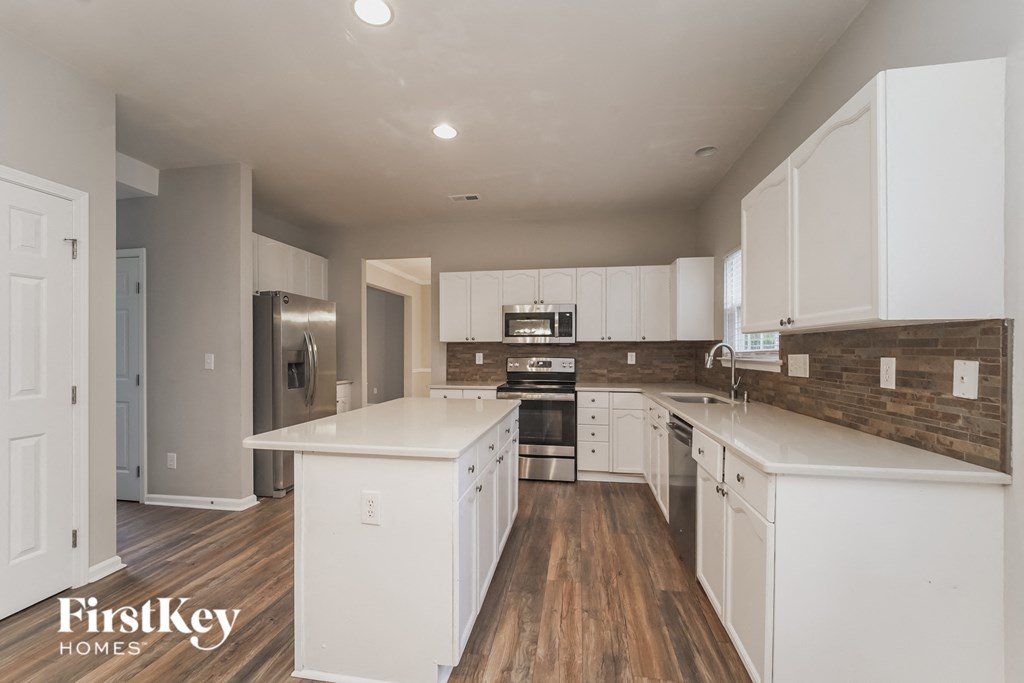 a white kitchen with white counters and white cabinets and a stainless steel refrigerator