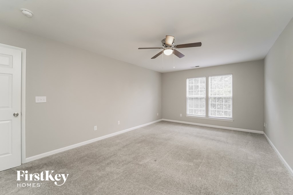 an empty living room with a ceiling fan and a window