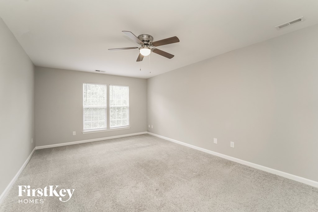 an empty living room with a ceiling fan and a window