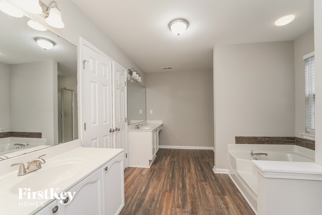 a white bathroom with a tub and a sink and a mirror