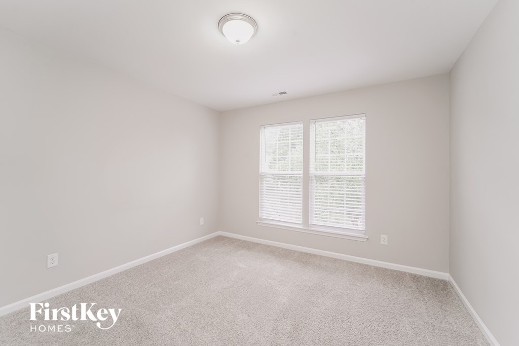 a bedroom with a carpeted floor and two windows