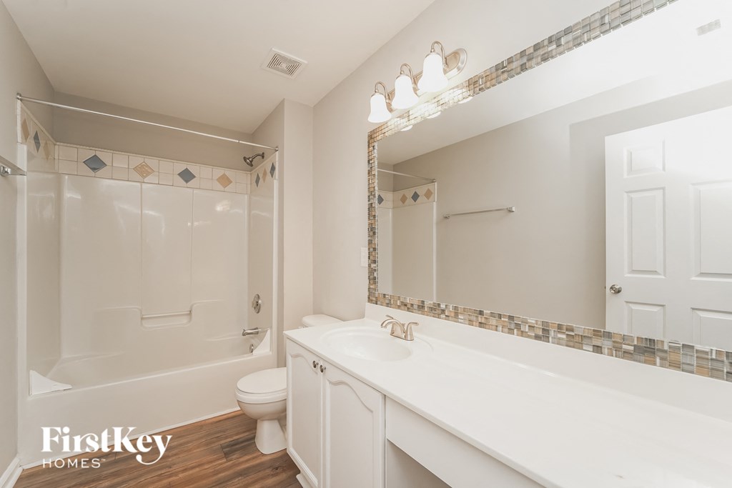 a white bathroom with a large mirror and a white toilet and sink
