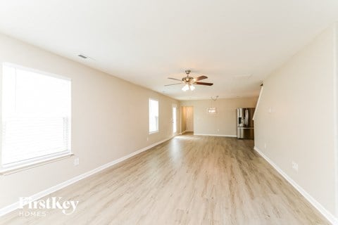 an empty living room with wood floors and a ceiling fan