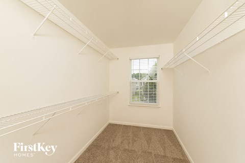 a spacious closet with shelves and a window in a white room