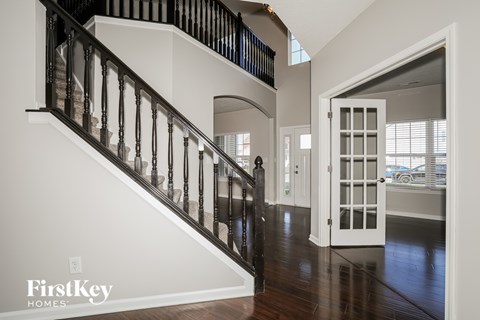 A staircase with a black railing and wooden steps leading to a white door.