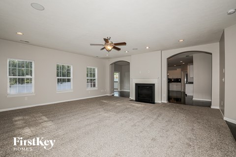 A spacious living room with a fireplace and a ceiling fan.