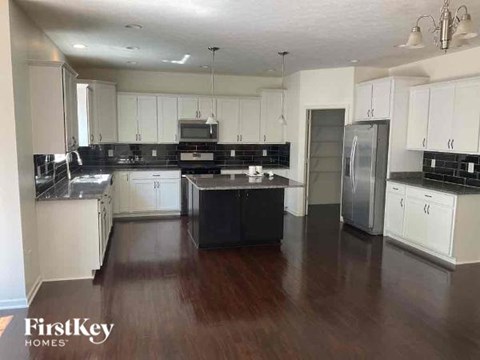 A kitchen with white cabinets and black countertops.