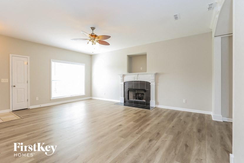 an empty living room with a fireplace and a ceiling fan