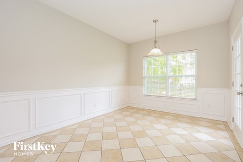an empty dining room with white walls and a window