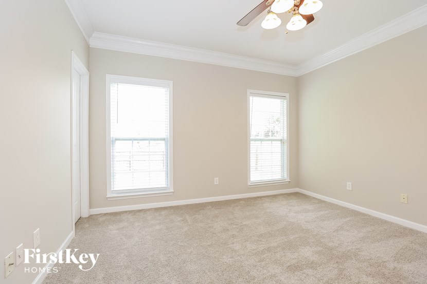 a empty living room with two windows and a ceiling fan