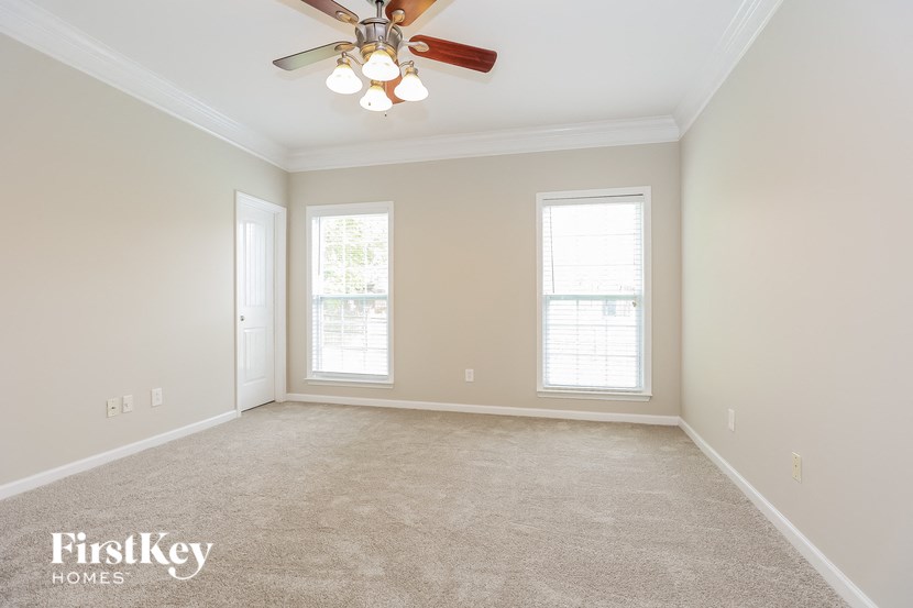 a empty living room with a ceiling fan and two windows