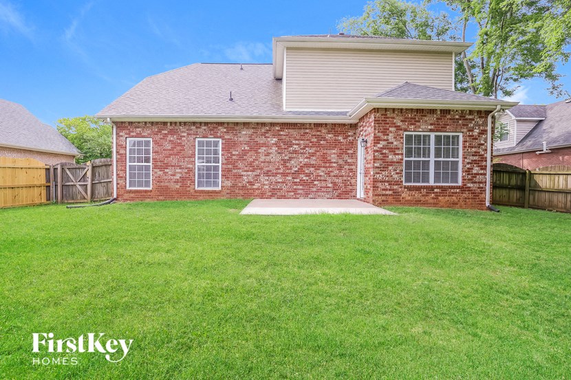 a backyard with a brick house and a lawn