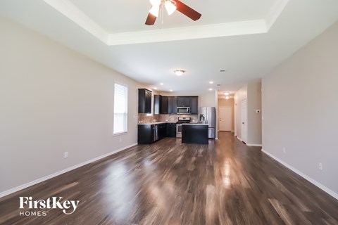 A spacious room with wooden floors and a ceiling fan.