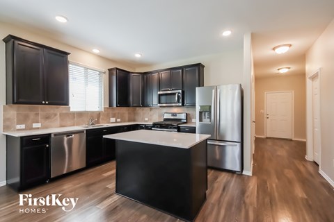 A modern kitchen with black cabinets and stainless steel appliances.