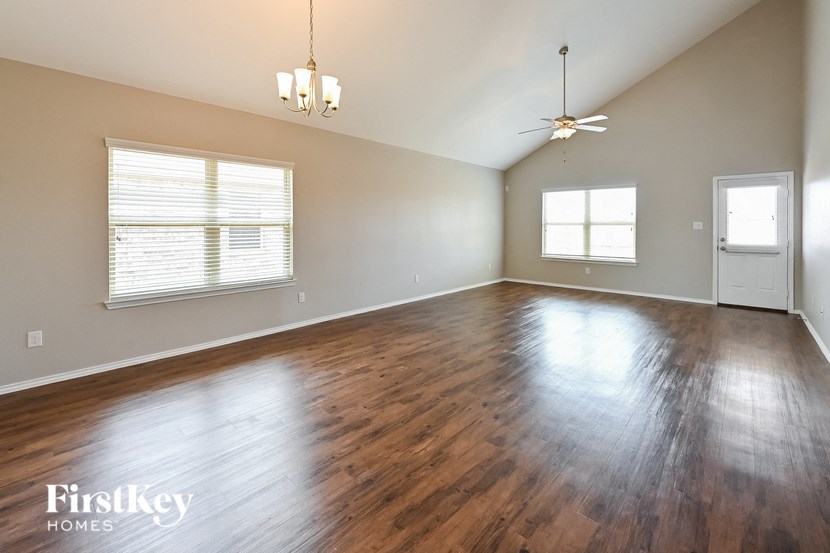 the living room of an empty house with wood floors and a ceiling fan