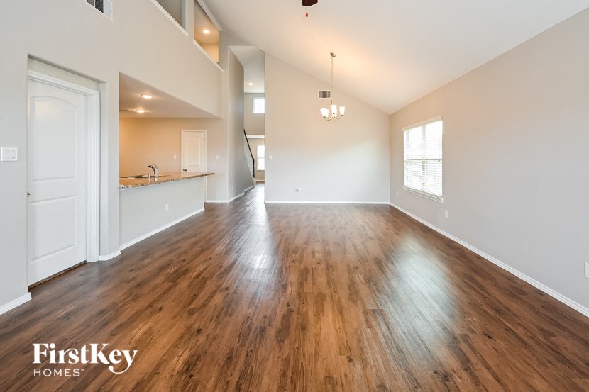 an empty living room and kitchen with wood flooring