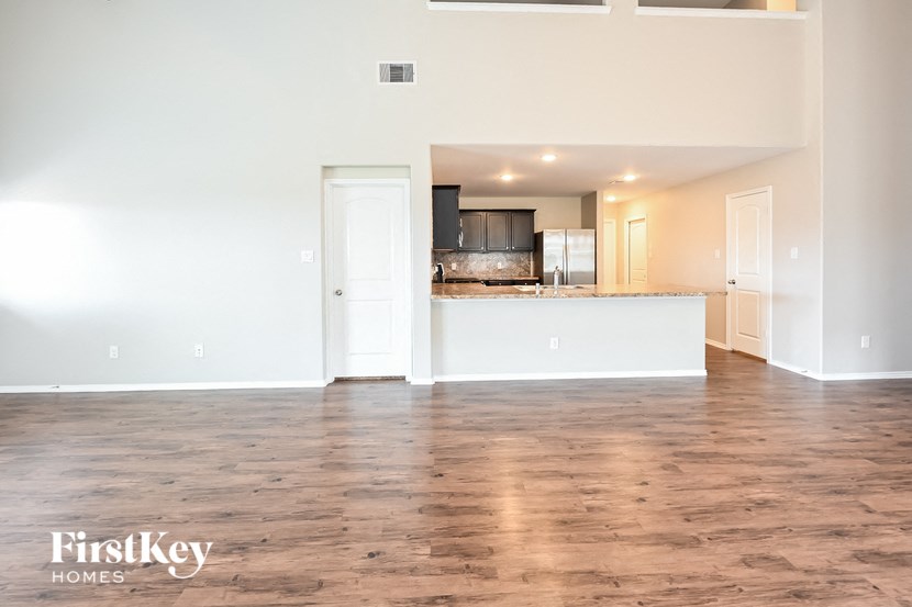 the living room and kitchen of an empty house with wood flooring