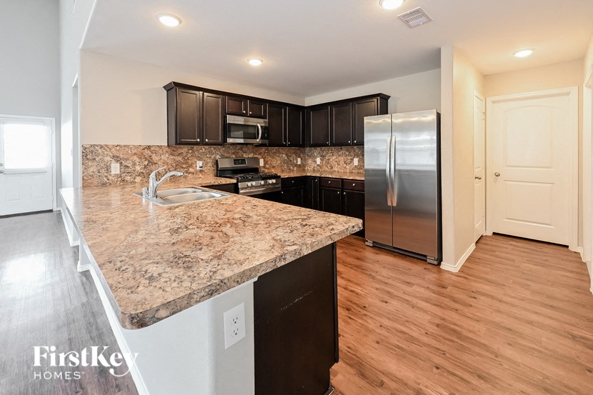 a kitchen with granite countertops and a stainless steel refrigerator