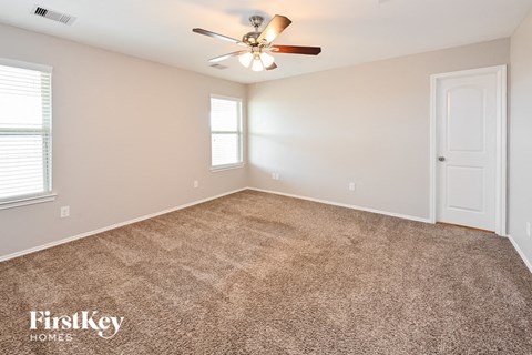 the spacious living room with carpet and a ceiling fan