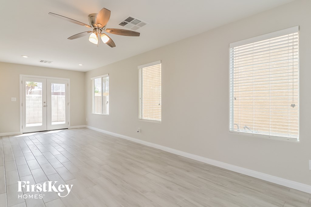 an empty living room with a ceiling fan and a window