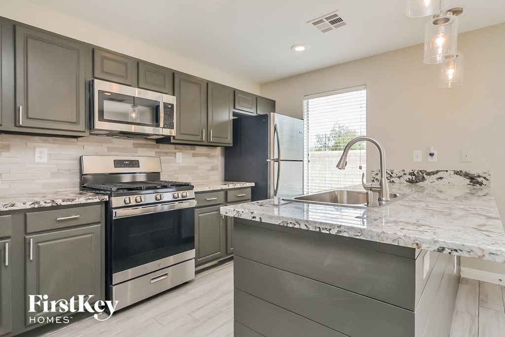an updated kitchen with stainless steel appliances and marble counter tops
