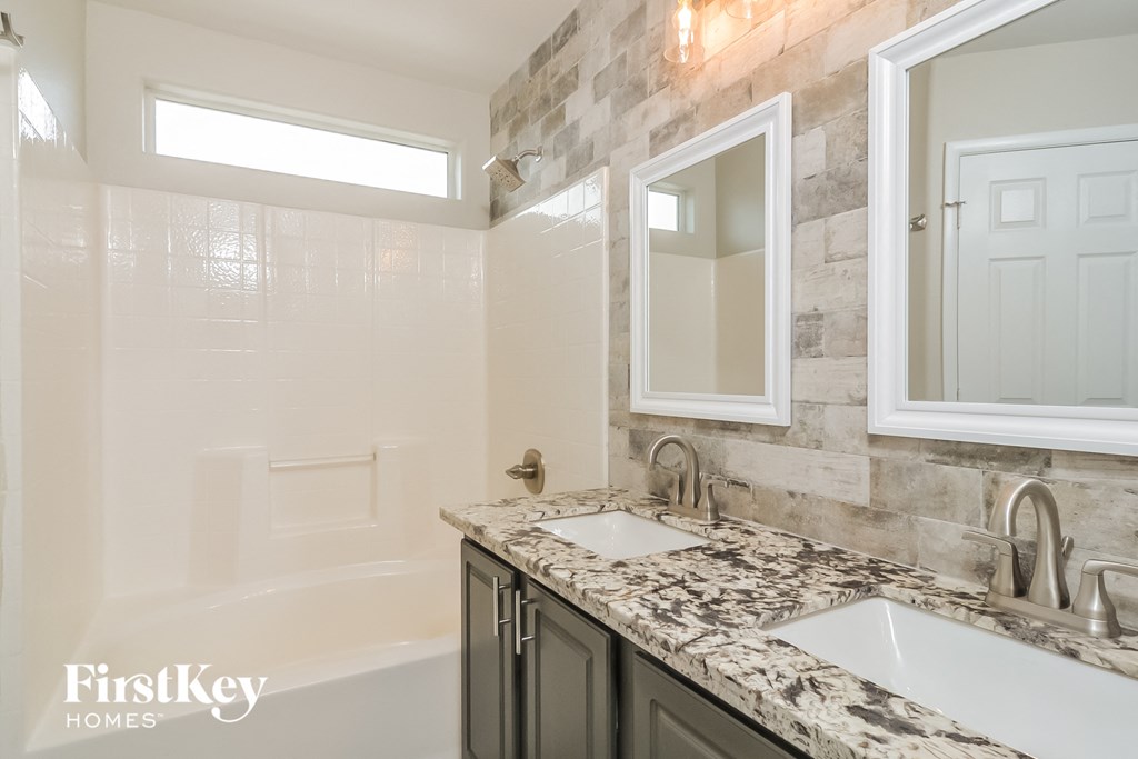 a bathroom with two sinks and a tub and a mirror