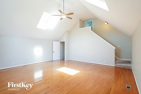an empty living room with wood floors and a ceiling fan