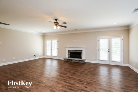 an empty living room with a ceiling fan and a fireplace