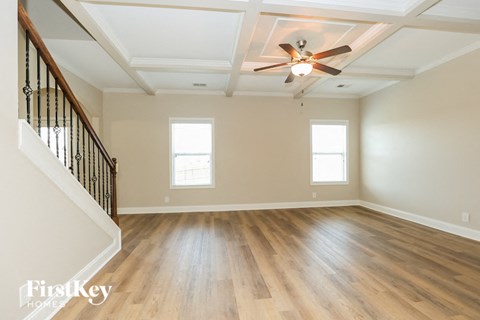 an empty living room with hardwood floors and a ceiling fan
